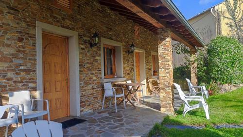 een stenen huis met een tafel en stoelen op een patio bij Mascotas Brais in San Miguel de Reinante