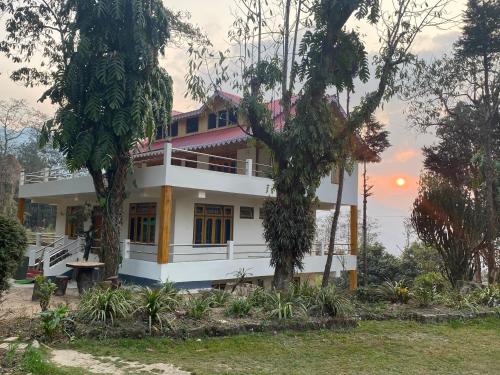 a house with the sunset in the background at Bloomfield Farmhouse and Eco-Resort in Darjeeling