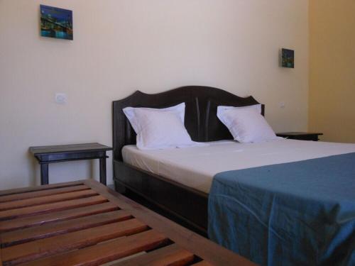 1 dormitorio con 1 cama con almohadas blancas y 2 mesas en SAARA HOTEL en Mahajanga