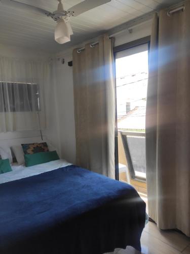 1 dormitorio con cama y ventana grande en Tardeli Suite dos anjos com sacada, en Arraial do Cabo