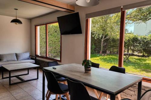 ein Wohnzimmer mit einem Tisch und Stühlen sowie einem großen Fenster in der Unterkunft Casa AICU in Villa La Angostura