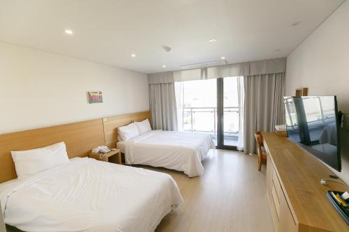 a hotel room with two beds and a flat screen tv at BK Hotel Jeju in Seogwipo