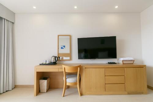 a room with a desk with a tv and a chair at BK Hotel Jeju in Seogwipo