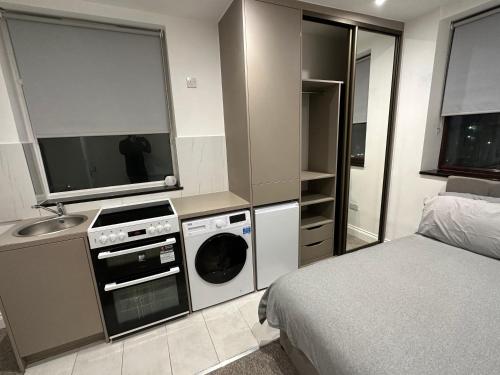 ein Schlafzimmer mit einem Bett, einem Waschbecken und einer Waschmaschine in der Unterkunft Unique Modern, 1 Bed Flat, 15 Mins To Central London in Hendon