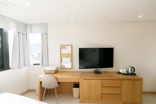 a bedroom with a desk with a television on it at BK Hotel Jeju in Seogwipo