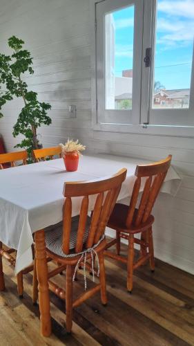 una mesa y sillas con una mesa blanca y una ventana en A Casinha de Madeira en Balneário Gaivotas