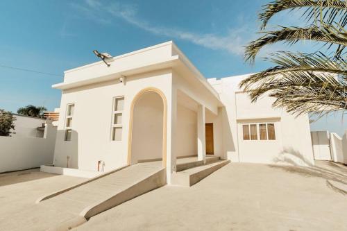 a white house with a palm tree in front of it at Alesea Baroro, La Union, Private Modern Villa with Pool, Jacuzzi, Beachfront View in Balio