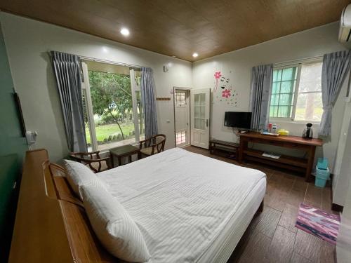 um quarto com uma grande cama branca e uma secretária em Happiness AIR B&B em Guanshan