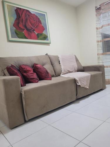 a brown couch with red pillows in a living room at Apartamento residencial in Blumenau