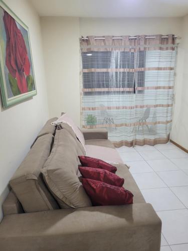 a couch with pillows in a living room with a window at Apartamento residencial in Blumenau