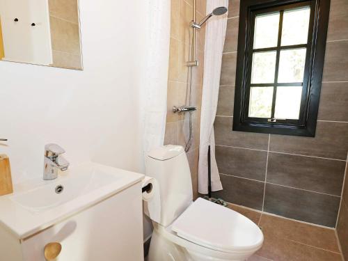 a bathroom with a toilet and a sink and a window at Holiday home Hadsund CXLIII in Hadsund