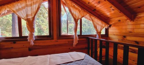 una camera da letto con finestre in una baita di tronchi di Villas de los Pinos 3 a Mazamitla