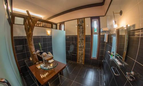 a bathroom with black tiled walls and a shower at The Sanctuary Langkawi in Pantai Cenang