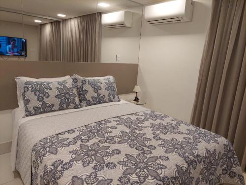 um quarto com uma cama com um cobertor e almofadas em Solar Tambaú - Loft sun and sea - ANÚNCIO NOVO em João Pessoa