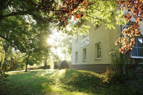 a building with the sun shining through the trees at Radduscher Hafen in Vetschau