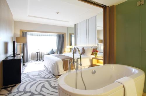 a hotel room with a tub and a bed at Centara Grand at Central Plaza Ladprao Bangkok in Bangkok