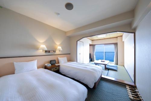 a hotel room with two beds and a large window at Hotel Resorpia Atami in Atami