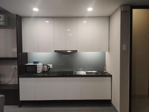 a kitchen with white cabinets and a sink and a microwave at Morden Bathtub Apartment in Ho Chi Minh City
