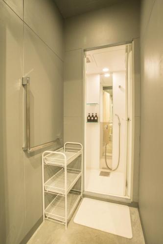 a bathroom with a shower and a towel rack at Hostel STAND BY ME in Fukuoka