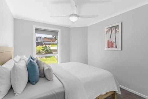 biała sypialnia z łóżkiem z poduszkami i oknem w obiekcie Waterford House w mieście North Creek