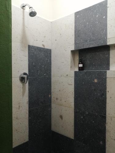 a bathroom with a shower with black and white tiles at La Morada, una ventana al golfo - Hotel boutique in Monte Gordo