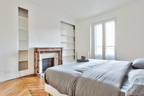 Dormitorio blanco con cama y chimenea en Appartement Quartier Le Marais 1 en París