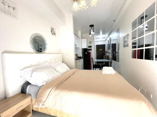 a white bedroom with a large bed and a table at Camella Northpoint Condo Studio in Davao City