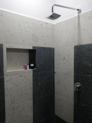 a bathroom with a shower with black and white tiles at La Morada, una ventana al golfo - Hotel boutique in Monte Gordo