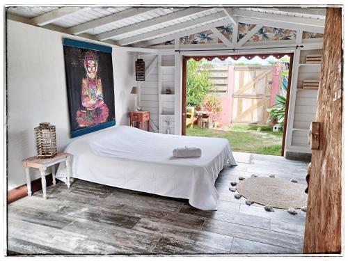 1 dormitorio con 1 cama y una pintura en la pared en LA CABANE D'artiste, en Cul de Sac