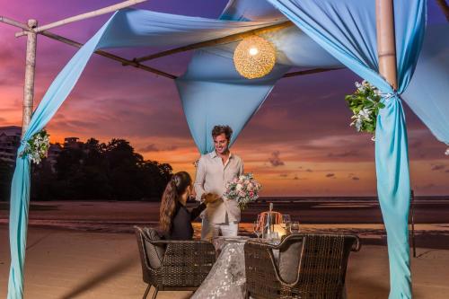 Ein Mann steht vor einem Tisch am Strand. in der Unterkunft Phuket Marriott Resort and Spa, Nai Yang Beach in Nai Yang Beach