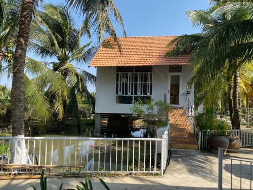 a house with a white fence and palm trees at Khách sạn Ngọc Bích 2 in Thôn Tân Hội