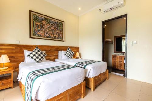 a bedroom with two beds and a television in it at Meruhdani Boutique Hotel Ubud in Ubud