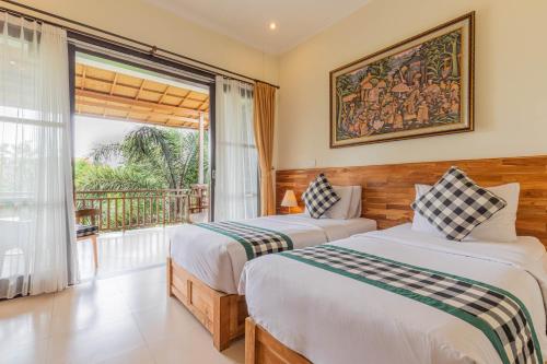 two beds in a room with a balcony at Meruhdani Boutique Hotel Ubud in Ubud