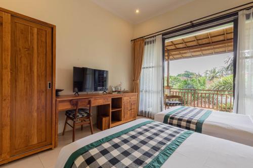 a bedroom with two beds and a desk with a television at Meruhdani Boutique Hotel Ubud in Ubud