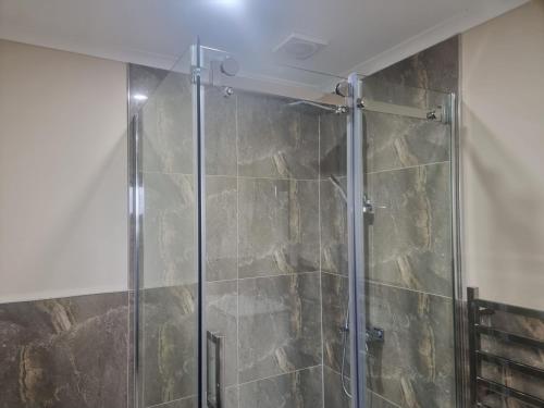 y baño con ducha y puerta de cristal. en 3 Bedroom Holiday Apartment Peninsula Park en Auckland