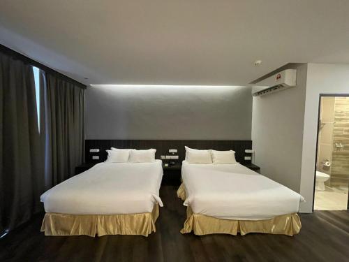 two beds in a hotel room with white sheets at Roxy Hotel Serian in Serian