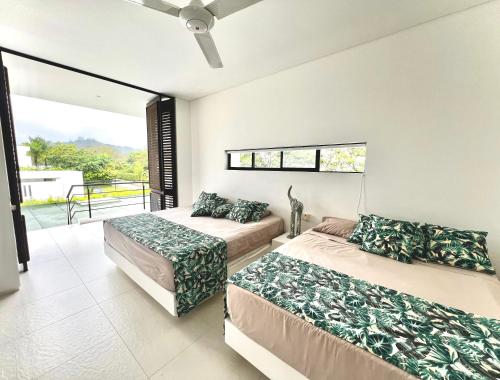 a bedroom with two beds and a balcony at Casa campestre Solé mediterranea con piscina en Anapoima in Anapoima