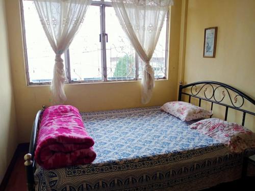 a bed in a room with a window and a bedspread at Darjeeling Home in Darjeeling