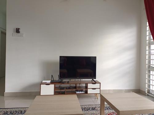 uma sala de estar com uma televisão de ecrã plano numa parede branca em Jannah Homestay Seruling em Putrajaya