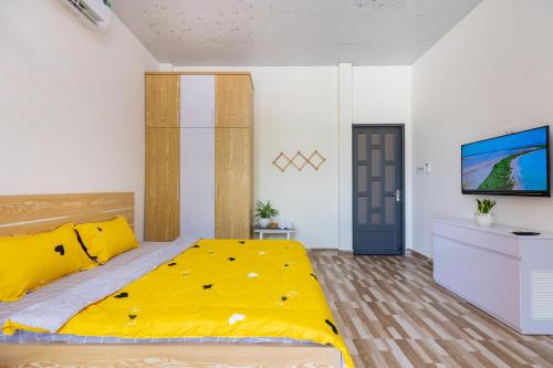 a bedroom with a yellow bed and a tv at MTV Homestay Vũng Tàu in Vung Tau