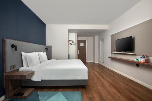 a bedroom with a white bed and a flat screen tv at Holiday Inn Express Shanghai Tangzhen by IHG - 20 mins to PVG Airport and Disney land in Shanghai