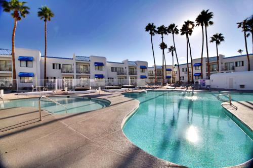 a swimming pool with palm trees in front of a building at Serene Vegas Boutique Hotel Las Vegas in Las Vegas