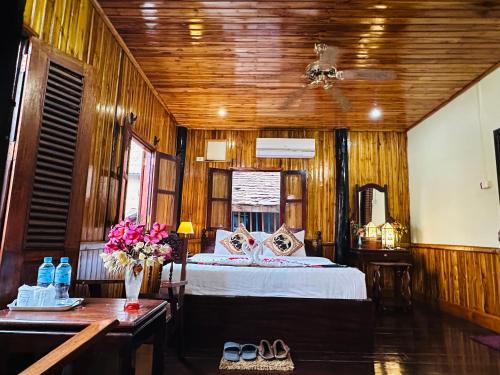 琅勃拉邦的住宿－Villa Alounsavath Mekong Riverside，一间卧室配有一张床和一张鲜花桌
