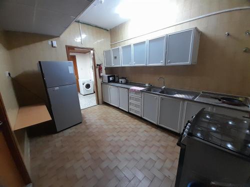 Una cocina con gabinetes blancos y un refrigerador. en Admf#101, en Abu Dabi