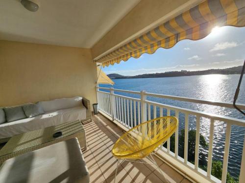 a balcony with a couch and a chair and the water at Magnifique appartement, vue mer in Noumea