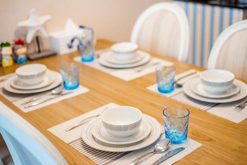 a wooden table with plates and dishes on it at Hua Hin My Resort 3BR Family Condo Free Water Park Walk to Beach & Cicada Night Market หัวหิน ห้องแฟมมิลี่ 3 ห้องนอน ฟรีสวนน้ำ ใกล้ทะเลและตลาดซิเคด้า in Hua Hin