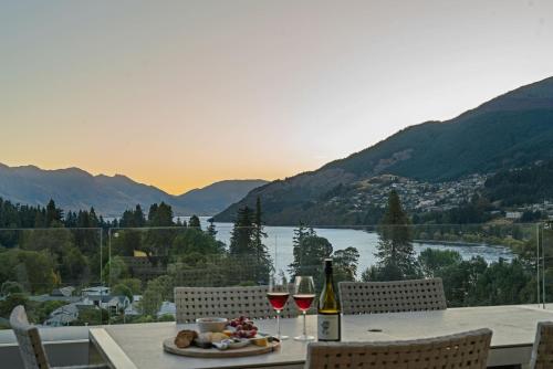 a table with wine glasses and a plate of food at Chic Central Penthouse & Spa by Staysouth in Queenstown