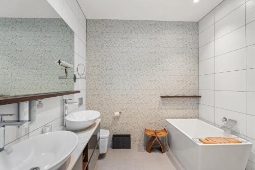 a bathroom with two sinks and a tub and a toilet at Chic Central Penthouse & Spa by Staysouth in Queenstown