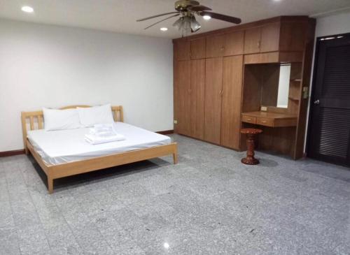 1 dormitorio con cama, mesa y ventilador de techo en โชคชัยแมนชั่น บางบัวทอง en Nonthaburi