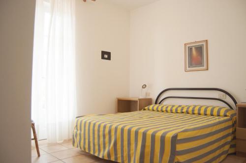 a bedroom with a bed with a yellow and blue striped blanket at Residence Le Mimose in Procchio